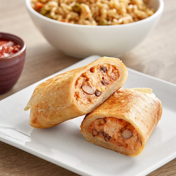 A Clara's Kitchen bean and cheese burrito on a plate with rice and vegetables.