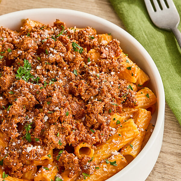 A bowl of pasta with V&V Supremo pork chorizo sticks and cheese on a table.