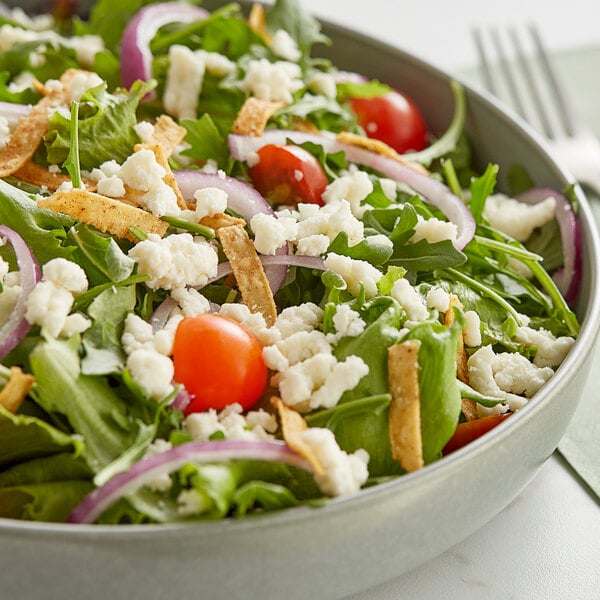 A bowl of salad with tomatoes and V&V Supremo Queso Fresco cheese crumbles.