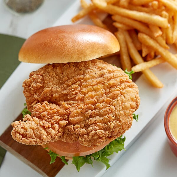 A fried Brakebush spicy breaded chicken sandwich with fries and sauce.