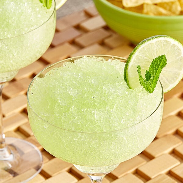 A glass with Goya guanabana pulp drink garnished with a lime wedge.