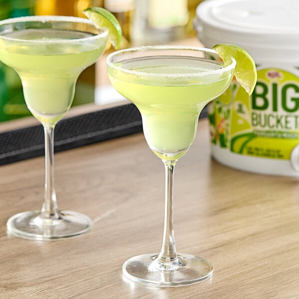 Two glasses of Master of Mixes margarita mix with yellow liquid in them on a table.