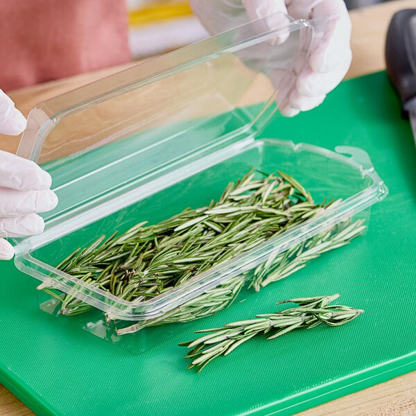 A hand holding a D&W Fine Pack plastic clamshell container of rosemary.