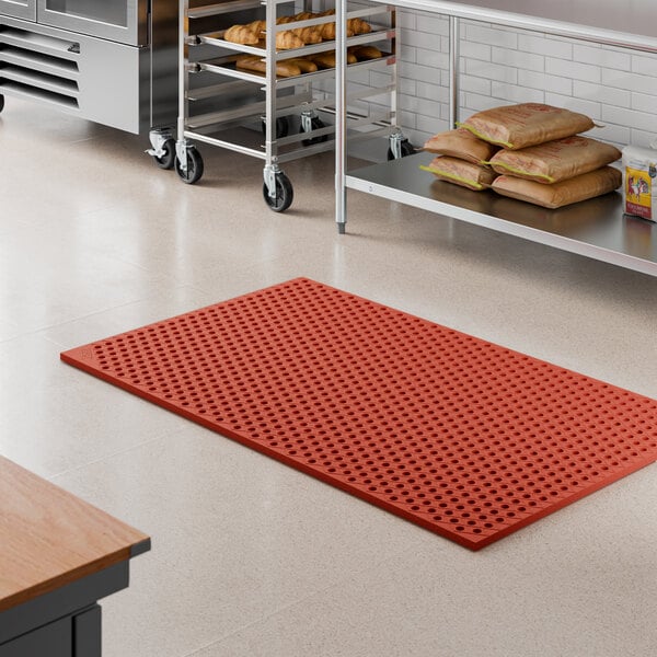 A red heavy-duty rubber anti-fatigue floor mat with a diamond pattern and straight edges, designed for grease resistance.