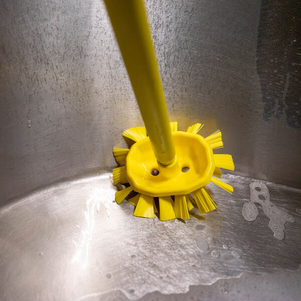A Vikan yellow tank brush head cleaning a stainless steel sink.