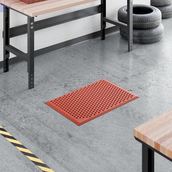 A red heavy-duty rubber anti-fatigue floor mat with a diamond pattern and beveled edge, measuring 2 feet by 3 feet and 1/2 inch thick.