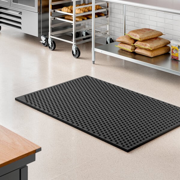 A heavy-duty black rubber anti-fatigue floor mat with a diamond pattern and straight edges, designed for commercial or kitchen use.