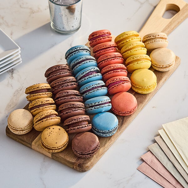 A group of colorful White Toque macarons on a wooden board.