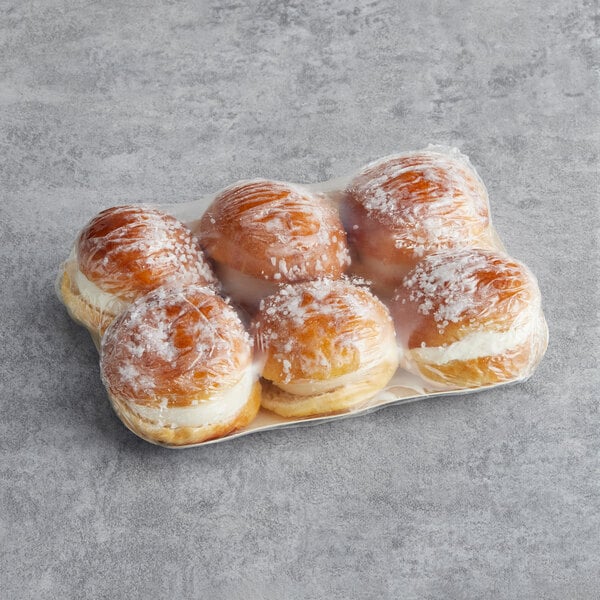 A plastic wrapped tray of White Toque mini Tropezienne pastries.