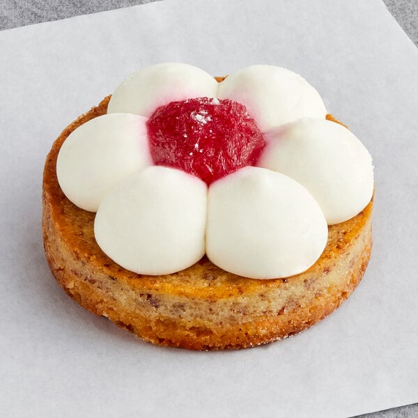 A White Toque cheese and raspberry tartlet with white and pink frosting and a flower on top.