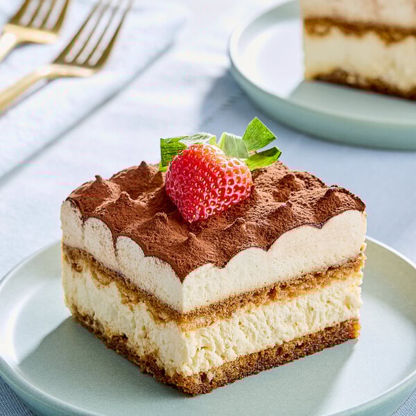 A piece of White Toque Tiramisu cake with a strawberry on top.