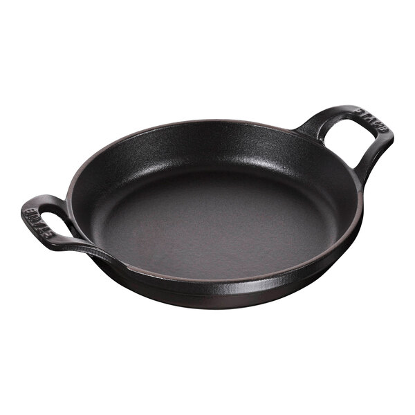 A black round Staub enameled cast iron pan with two handles.