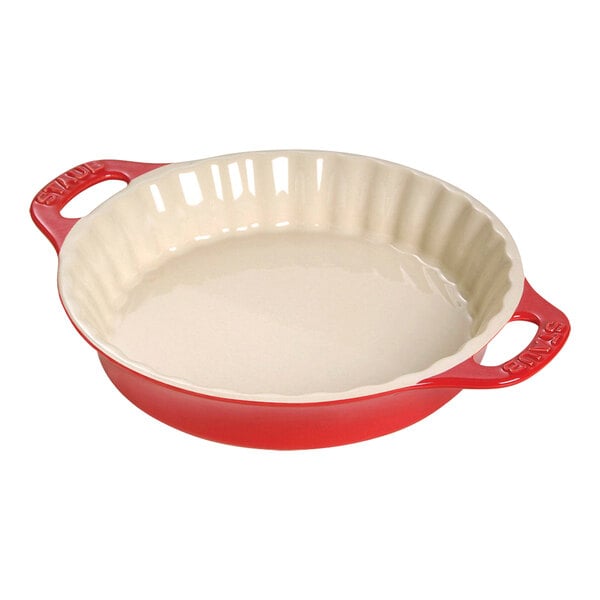 A red and white Staub ceramic pie dish with handles.