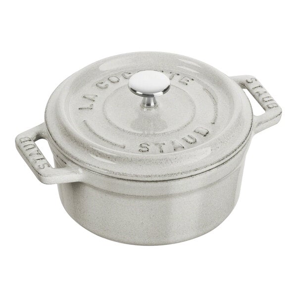 A white Staub enameled cast iron mini Dutch oven with a lid.