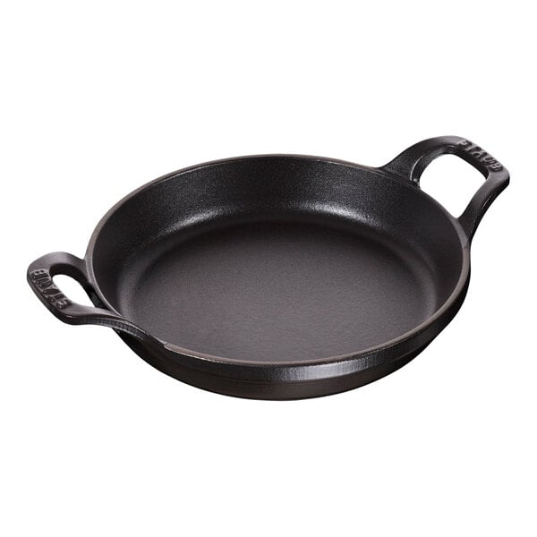 A black Staub enameled cast iron round pan with two handles.