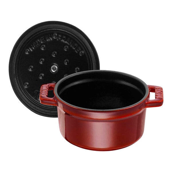 A red Staub enameled cast iron pot with a black lid.