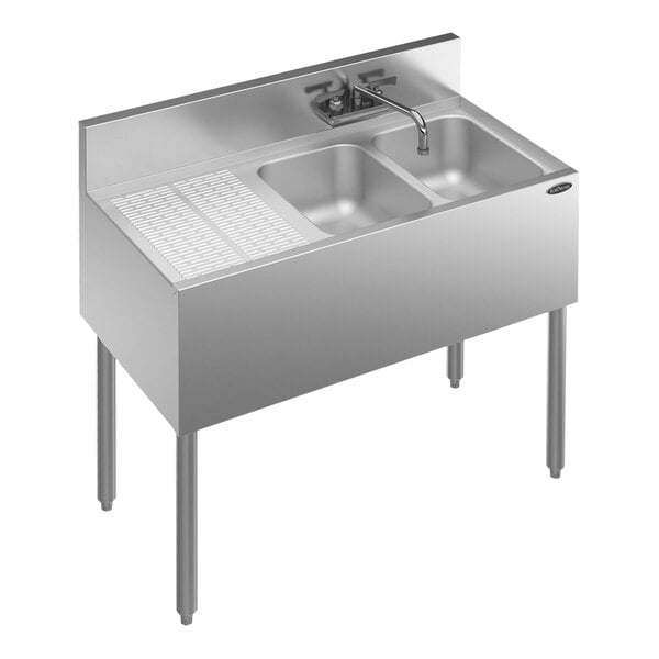 A Krowne stainless steel underbar sink with two bowls, a faucet, and a left drainboard.