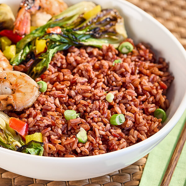 A bowl of Lotus Foods organic long grain red rice with shrimp and vegetables.