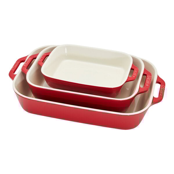 A stack of three red Staub ceramic baking dishes with lids.