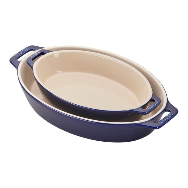 A Staub dark blue ceramic oval baking dish set with handles.