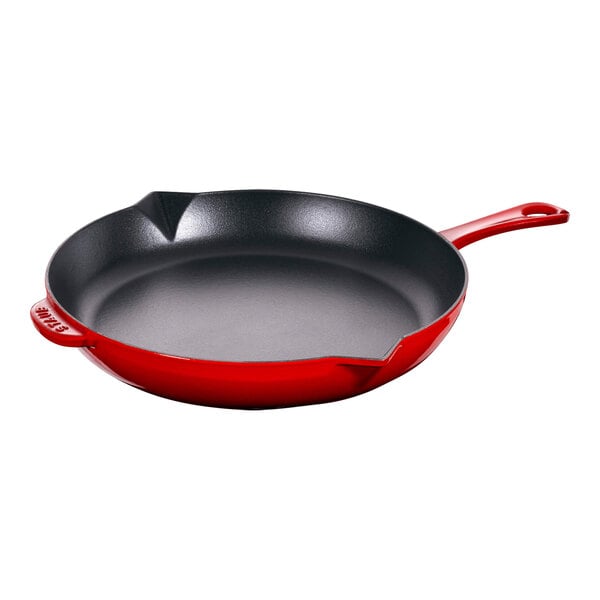 A Staub cherry enameled cast iron skillet with a handle.