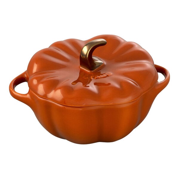 A burnt orange ceramic pumpkin shaped mini casserole dish with a gold stem.