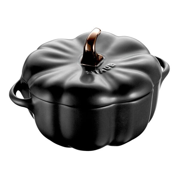 A black Staub ceramic pumpkin mini pot with a handle.