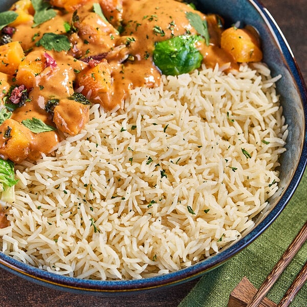 A bowl of Lotus Foods long grain white basmati rice with chopsticks on a table.