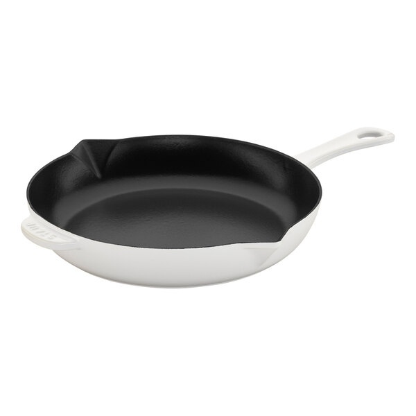 A black and white Staub enameled cast iron skillet with a handle.