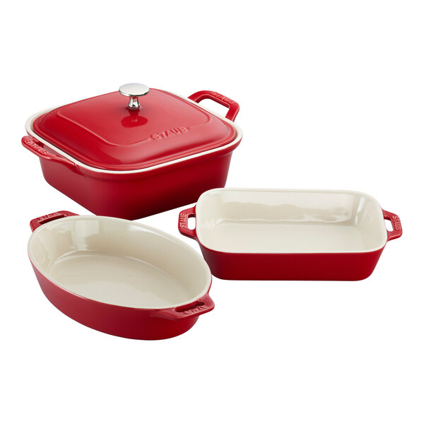 A group of red and white Staub baking dishes, including oval and rectangular dishes.