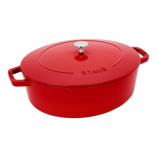 A Staub cherry red enameled cast iron oval Dutch oven with a lid.