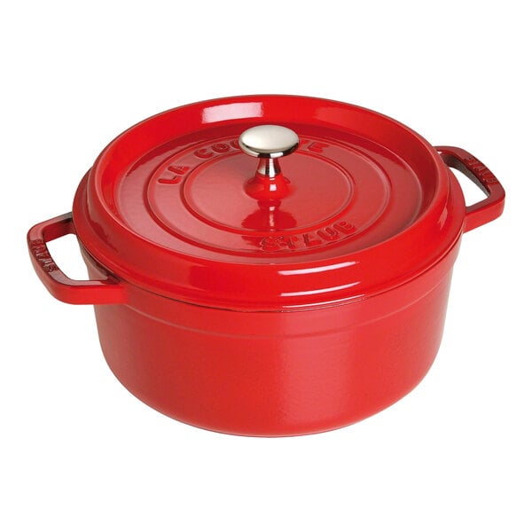 A Staub cherry red enameled cast iron pot with a lid.