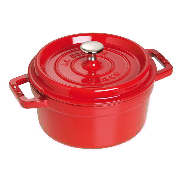 A Staub cherry red enameled cast iron pot with a lid.