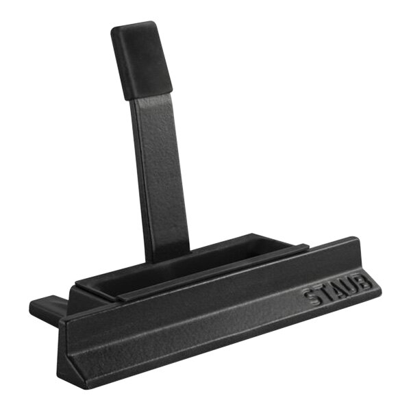 A black plastic Staub lid holder with a handle.