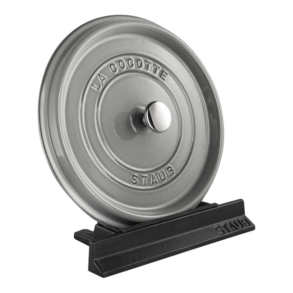 A round metal disc with a black handle.