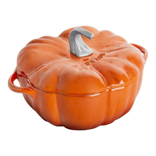 A Staub burnt orange pumpkin enameled cast iron pot with a handle.