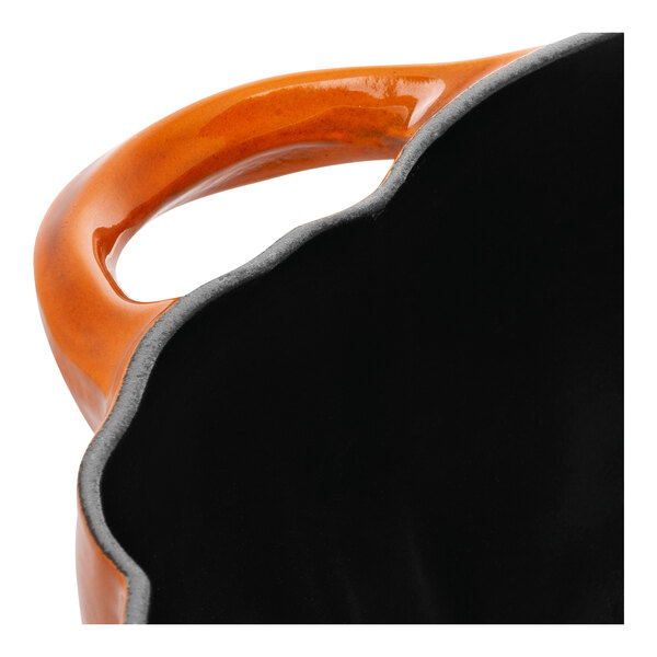 A burnt orange and black Staub enameled cast iron pot with a handle.