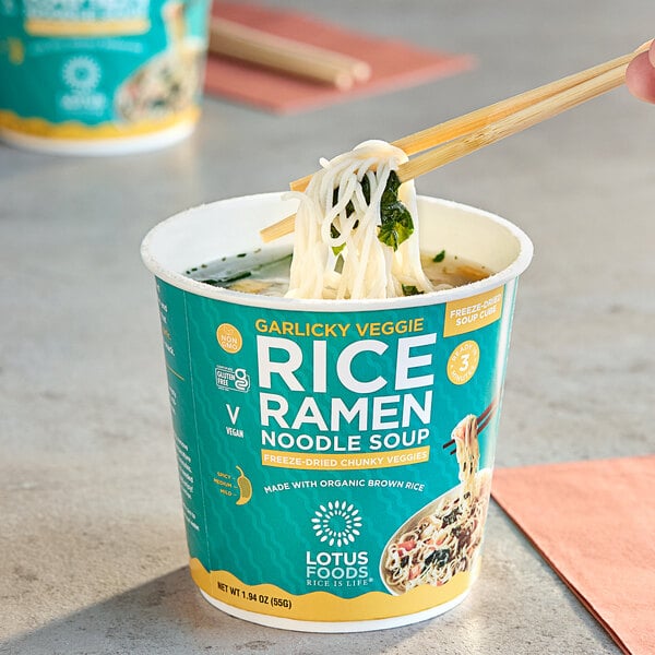 A person using chopsticks to eat Lotus Foods Garlicky Vegetable Rice Ramen from a cup.