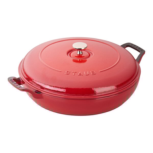 A Staub cherry red enameled cast iron round pot with a lid.