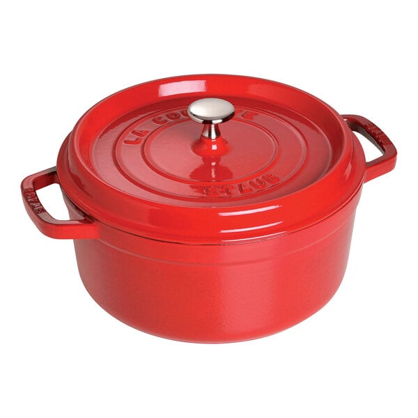 A Staub cherry red enameled cast iron pot with a lid.
