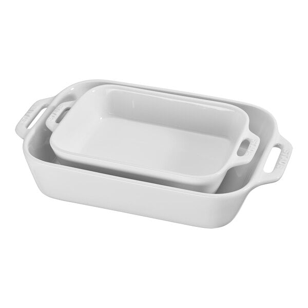 A stack of white rectangular Staub baking dishes with two handles.
