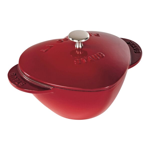 A Staub cherry red enameled cast iron pot with a lid.