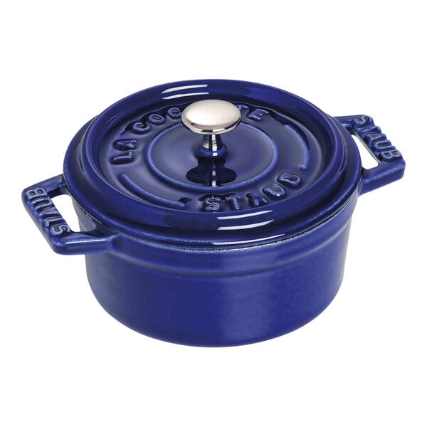 A dark blue Staub enameled cast iron mini Dutch oven with a lid and handle.