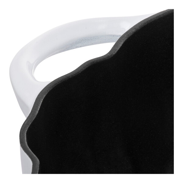 A white Staub enameled cast iron pot with a pumpkin shape and black accents.