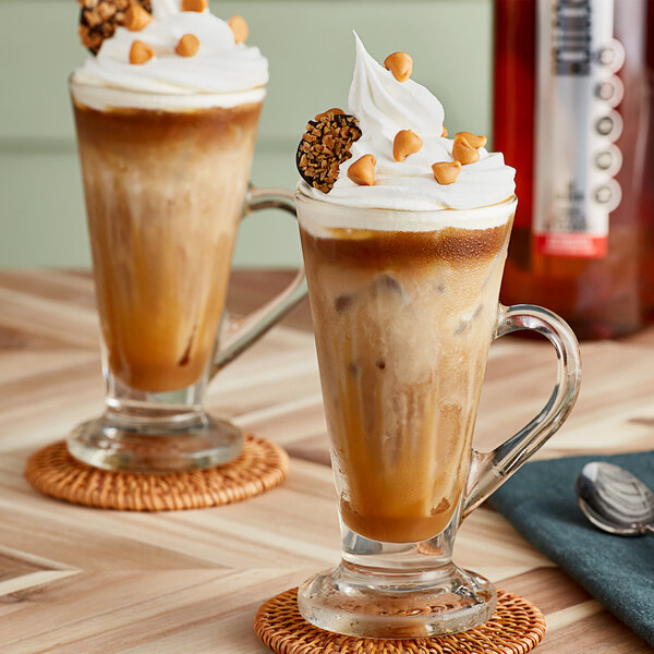 A glass cup of coffee with SHOTT Butterscotch Flavoring Syrup on a table.