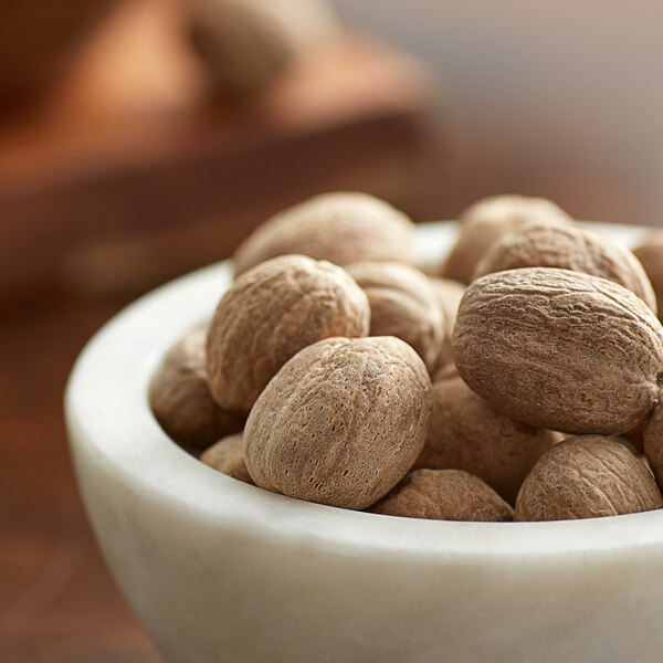 A bowl of whole nutmeg sitting on a table.