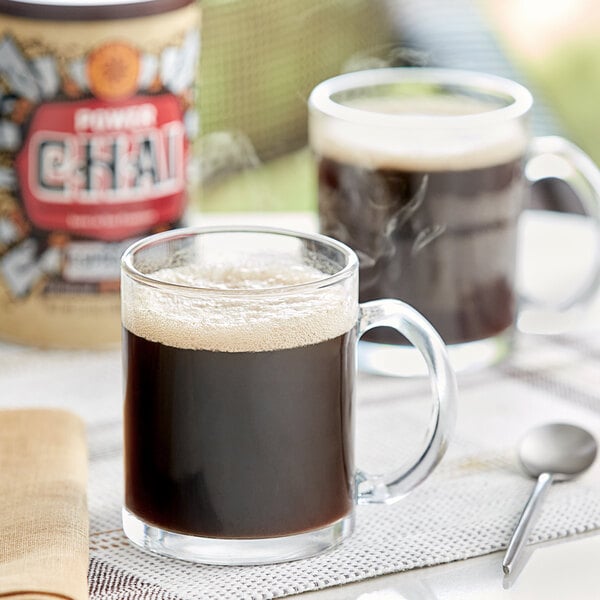 A table with a glass mug of brown David Rio Power Chai Tea Latte with Espresso and a spoon.