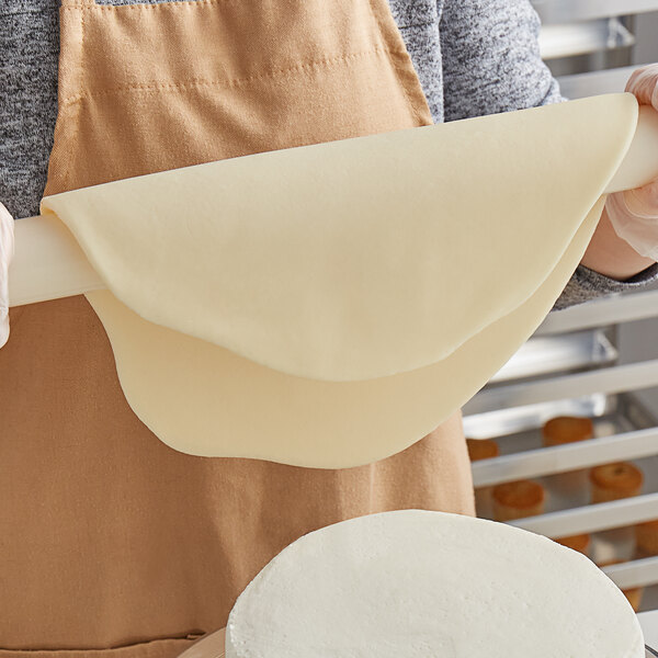 A person rolling out Satin Ice chocolate-flavored fondant with a rolling pin.
