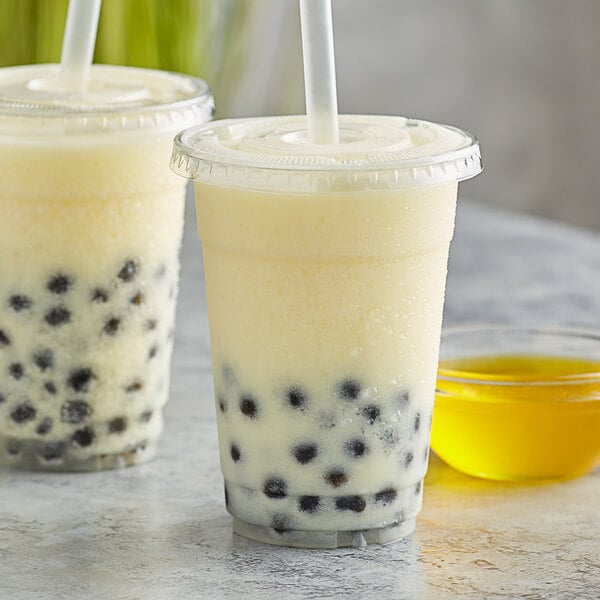 Two cups of kumquat bubble tea with straws on a white background.