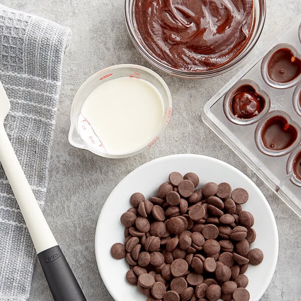 A bowl of Callebaut dark chocolate sauce with chocolate chips on the side.